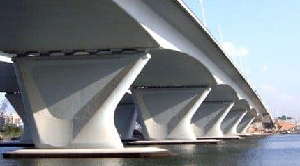 Row of tapered reinforced-concrete bridge piers supporting a viaduct deck over water.